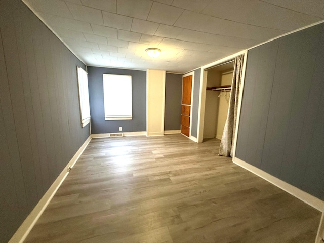 unfurnished bedroom with wood-type flooring and wooden walls