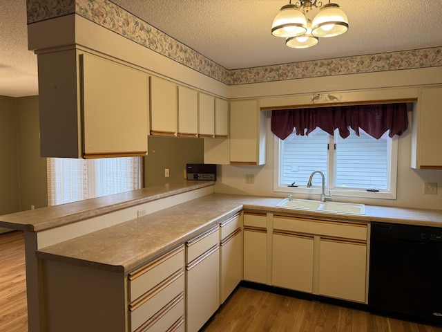 kitchen with sink, a textured ceiling, black dishwasher, light hardwood / wood-style floors, and kitchen peninsula