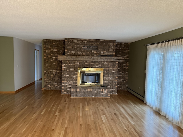 unfurnished living room with a baseboard heating unit, a textured ceiling, a fireplace, and hardwood / wood-style floors