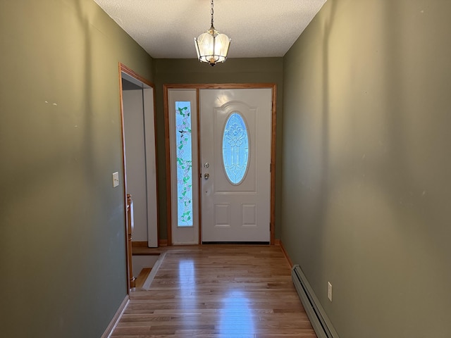 foyer featuring a textured ceiling, light wood-type flooring, and baseboard heating