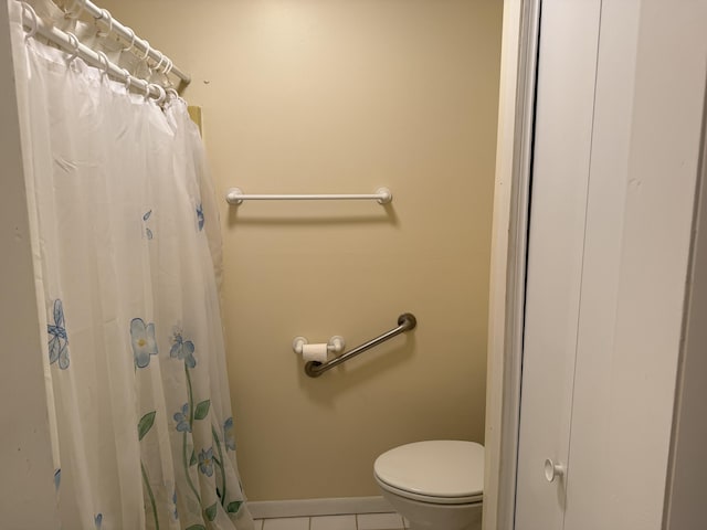 bathroom with toilet, curtained shower, and tile patterned floors