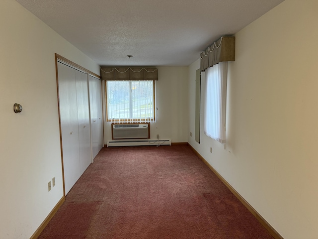 unfurnished bedroom with baseboard heating, a closet, carpet, a wall mounted AC, and a textured ceiling