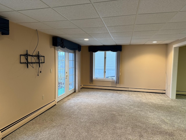 carpeted spare room with a paneled ceiling, french doors, and a baseboard heating unit