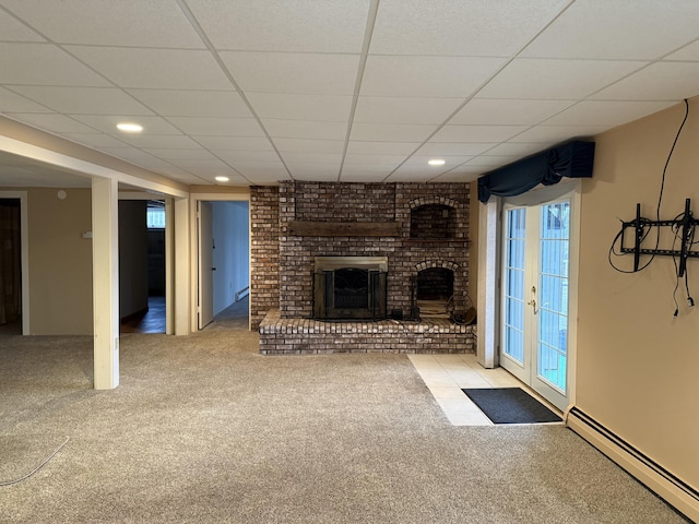 unfurnished living room with a drop ceiling, french doors, a brick fireplace, carpet flooring, and a baseboard radiator