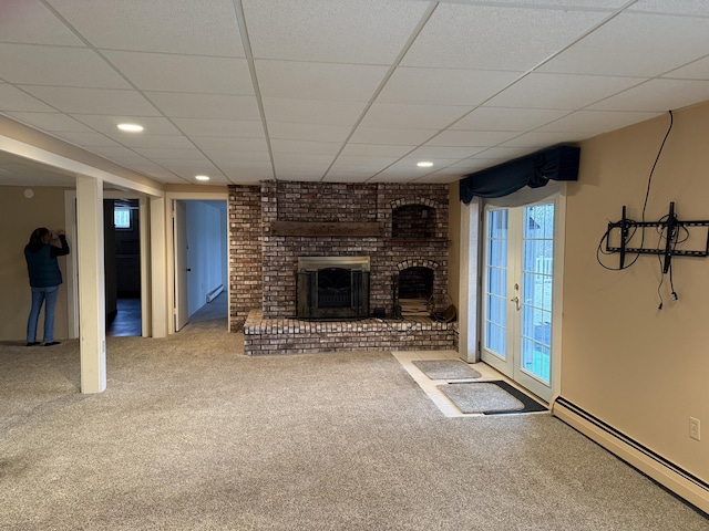 unfurnished living room with a baseboard heating unit, french doors, a brick fireplace, and carpet