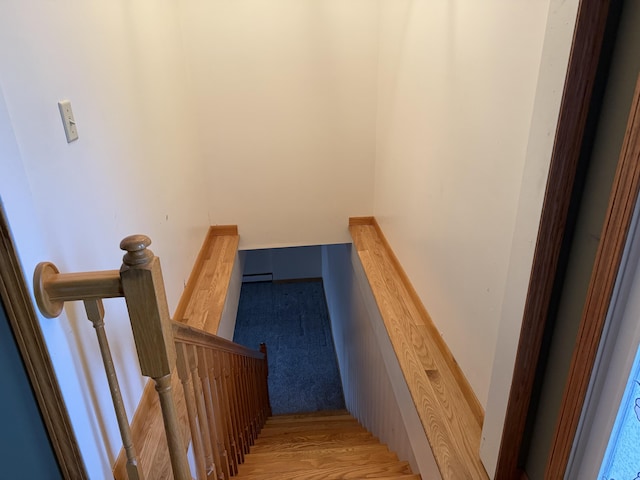 stairway with a baseboard radiator and hardwood / wood-style floors