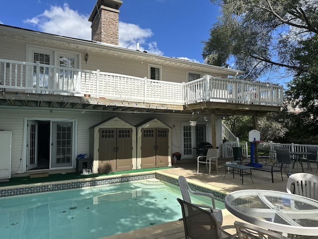 rear view of house with a swimming pool side deck, a patio, and a fire pit