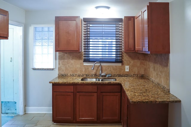 kitchen featuring stone countertops, light tile patterned floors, sink, and tasteful backsplash