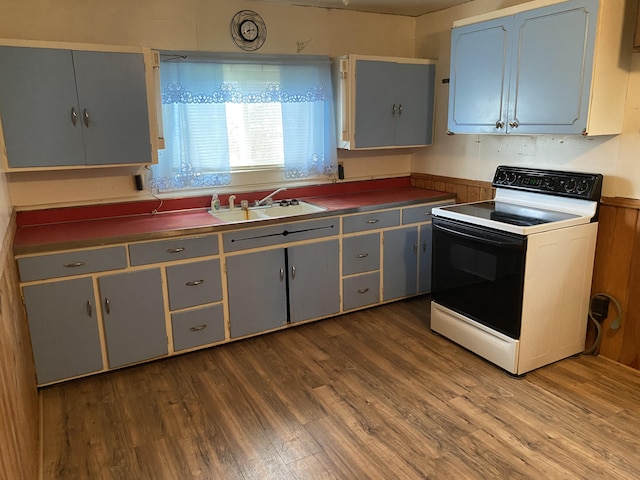 kitchen featuring white electric range oven, hardwood / wood-style flooring, gray cabinetry, and sink