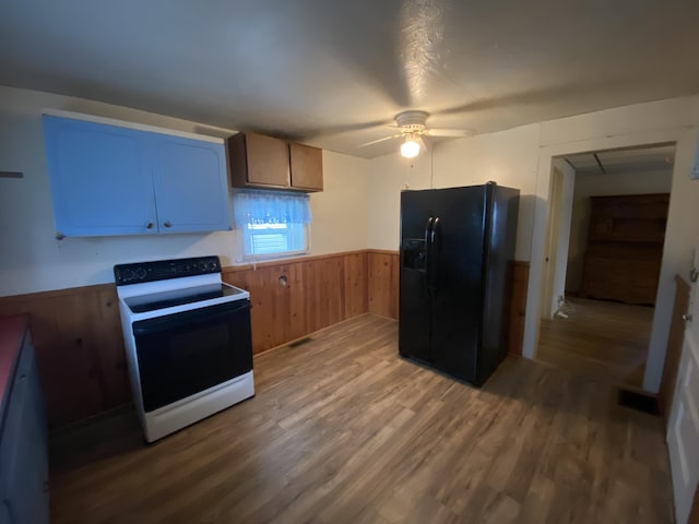 kitchen featuring black fridge, white electric range oven, ceiling fan, wooden walls, and wood-type flooring