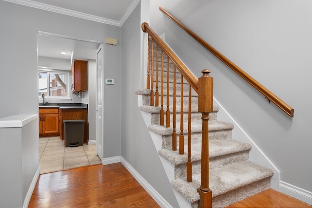 staircase with hardwood / wood-style flooring, sink, and crown molding