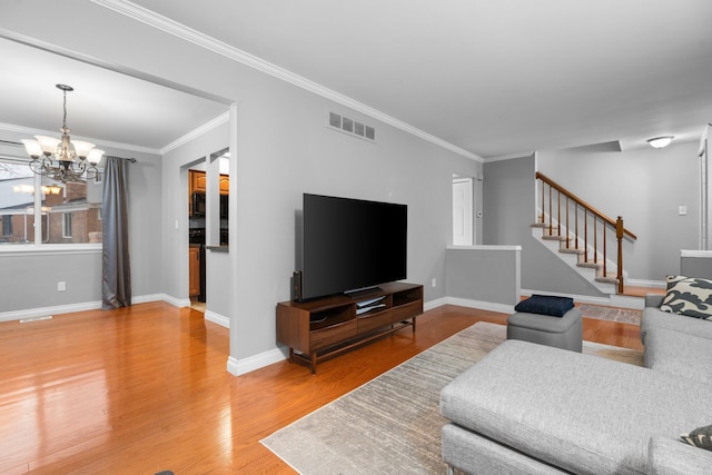 living room with hardwood / wood-style floors, crown molding, and a notable chandelier