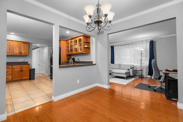 home office with light hardwood / wood-style floors, ornamental molding, and an inviting chandelier