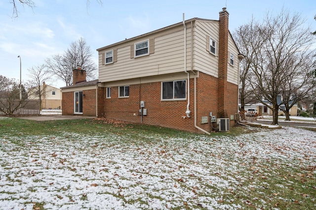 snow covered rear of property with central air condition unit