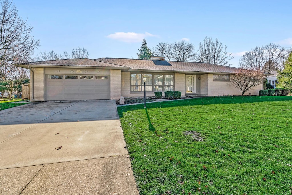 ranch-style home featuring a garage and a front lawn