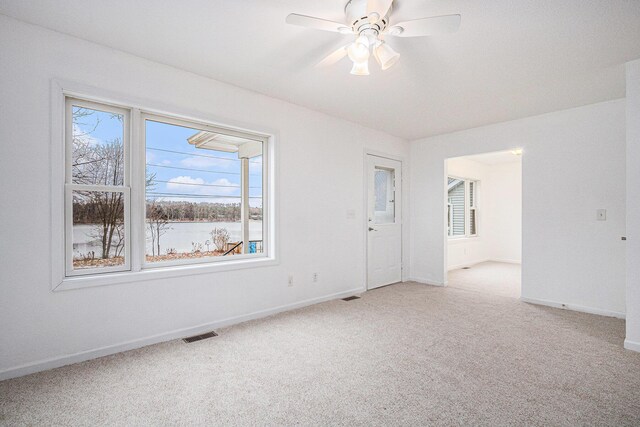 unfurnished room featuring a wealth of natural light, carpet, and ceiling fan