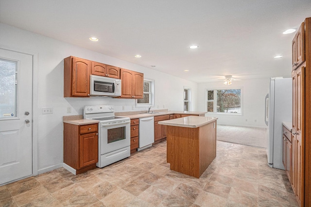 kitchen featuring ceiling fan, a center island, white appliances, and sink