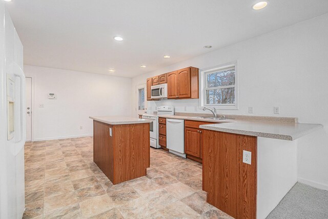 kitchen featuring kitchen peninsula, a kitchen island, white appliances, and sink