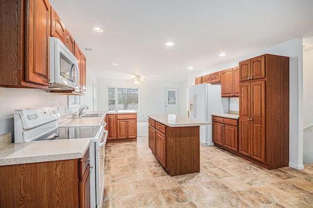 kitchen with ceiling fan, sink, kitchen peninsula, white appliances, and a kitchen island