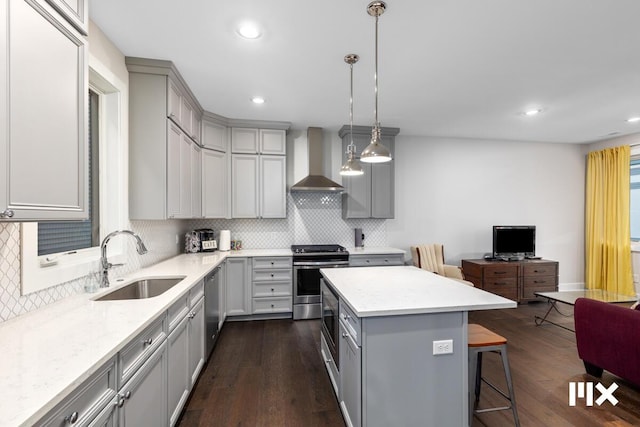 kitchen featuring gray cabinetry, a center island, wall chimney exhaust hood, and appliances with stainless steel finishes