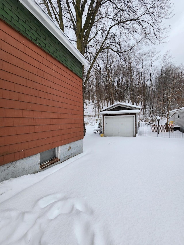 snowy yard featuring a garage and an outdoor structure