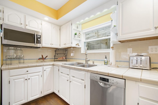 kitchen with decorative backsplash, appliances with stainless steel finishes, sink, tile countertops, and white cabinets