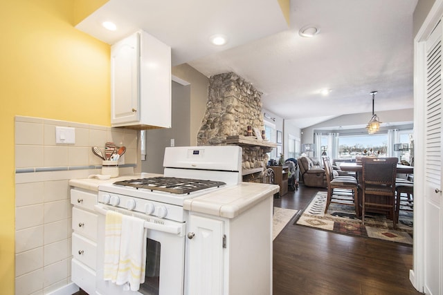 kitchen with vaulted ceiling, tile countertops, white cabinets, dark hardwood / wood-style floors, and white gas stove