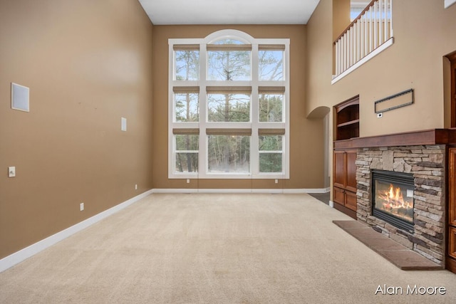 unfurnished living room featuring carpet floors, a fireplace, and a towering ceiling