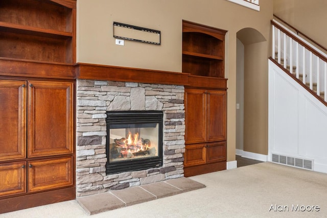 room details featuring built in shelves, a stone fireplace, and carpet