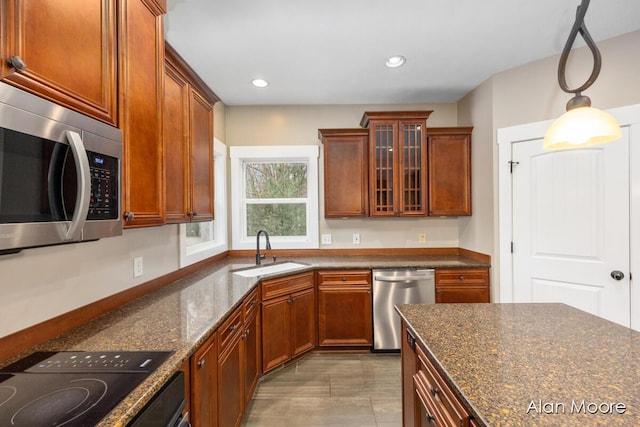 kitchen with appliances with stainless steel finishes, decorative light fixtures, dark stone counters, and sink