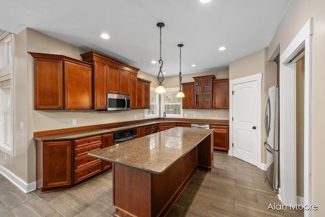 kitchen featuring appliances with stainless steel finishes, sink, stone countertops, decorative light fixtures, and a kitchen island