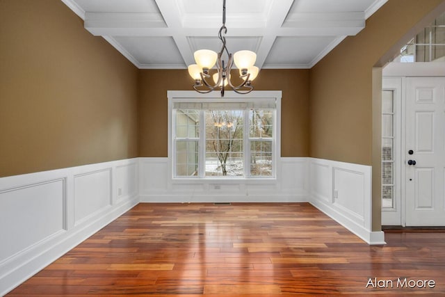 unfurnished dining area with a chandelier, wood-type flooring, crown molding, and beam ceiling