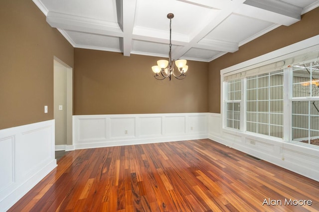 spare room featuring coffered ceiling, dark hardwood / wood-style floors, ornamental molding, beamed ceiling, and a notable chandelier