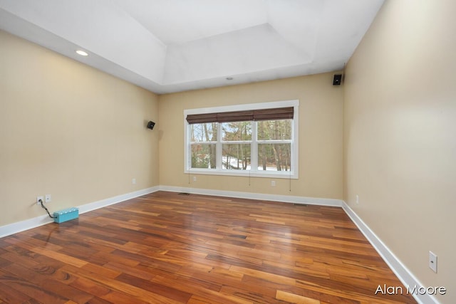 empty room with a raised ceiling and hardwood / wood-style floors