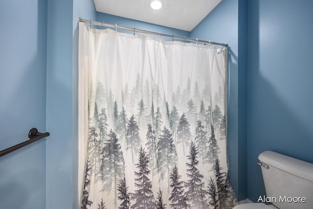 bathroom with curtained shower and toilet