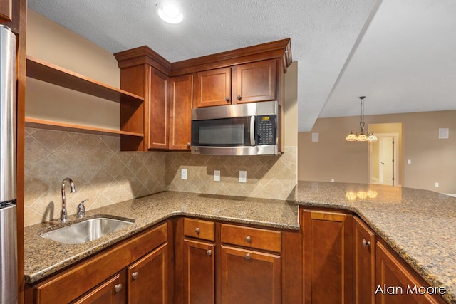 kitchen featuring tasteful backsplash, sink, dark stone counters, and decorative light fixtures