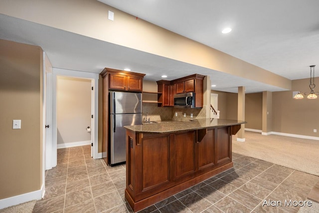 kitchen featuring kitchen peninsula, appliances with stainless steel finishes, tasteful backsplash, decorative light fixtures, and a notable chandelier