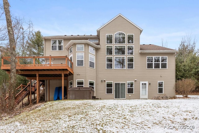 snow covered back of property featuring a hot tub and a deck