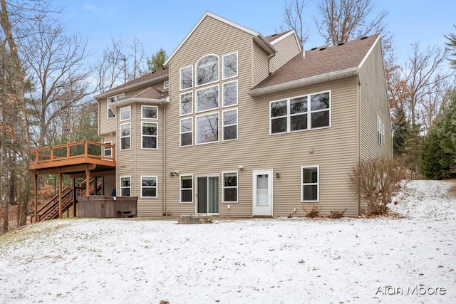 snow covered house featuring a deck and a hot tub