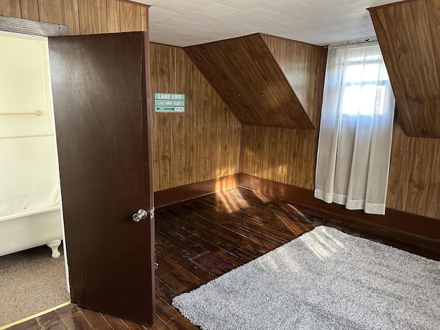 additional living space with wooden walls, dark hardwood / wood-style flooring, and vaulted ceiling