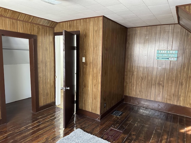 spare room with dark wood-type flooring and wooden walls