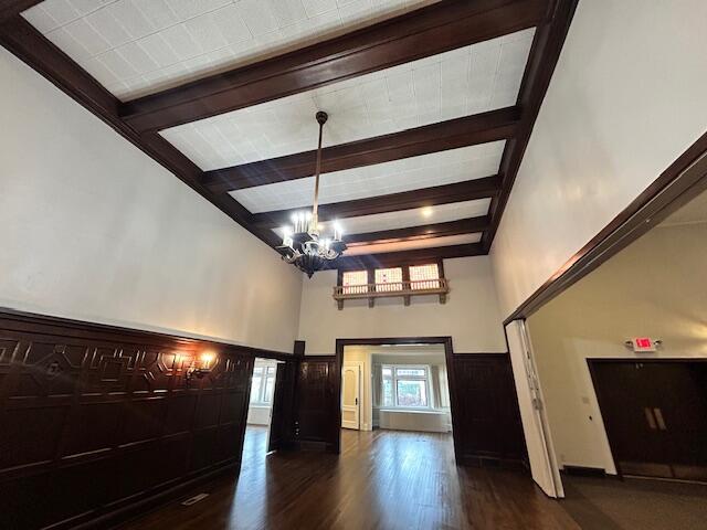 foyer with beam ceiling, dark wood-type flooring, and a chandelier