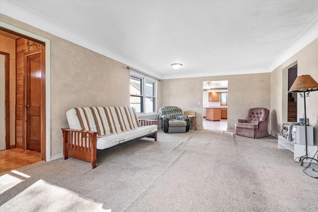 sitting room with ornamental molding and light carpet