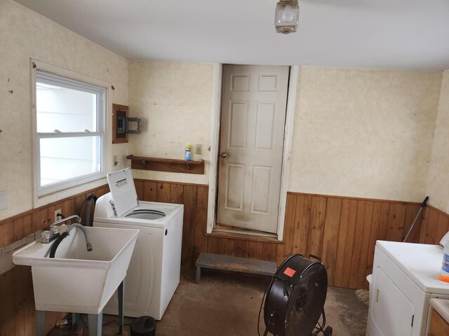 laundry area with sink, wood walls, and washing machine and clothes dryer