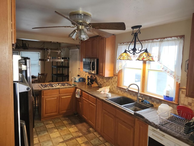 kitchen featuring ceiling fan, sink, tile countertops, decorative backsplash, and appliances with stainless steel finishes