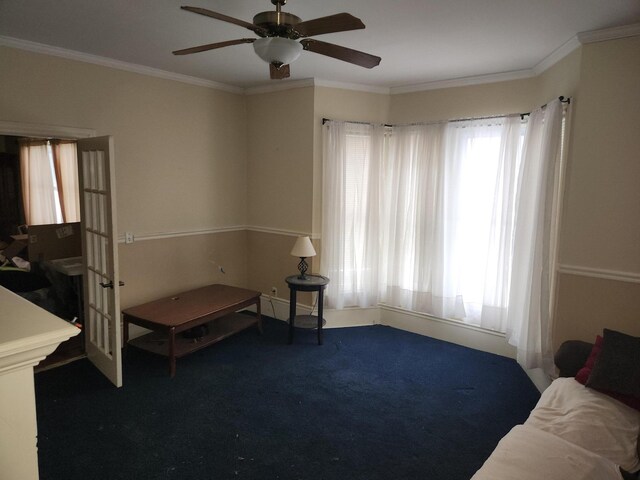 living area with ceiling fan, plenty of natural light, carpet floors, and ornamental molding