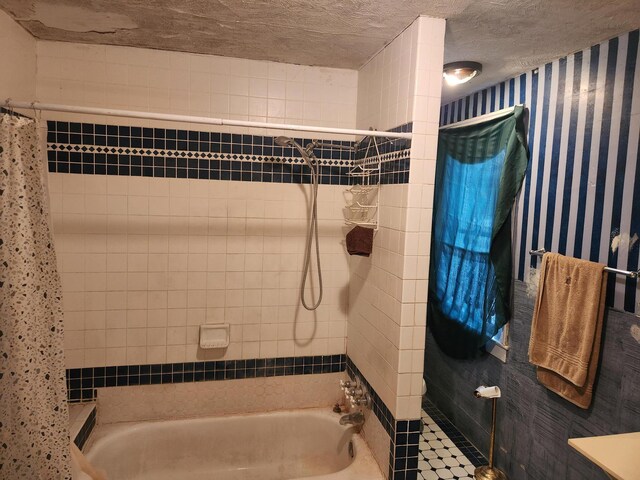 bathroom with a textured ceiling and tiled shower / bath