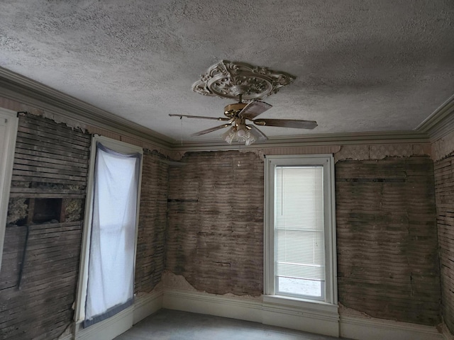 empty room with ceiling fan, a textured ceiling, and ornamental molding