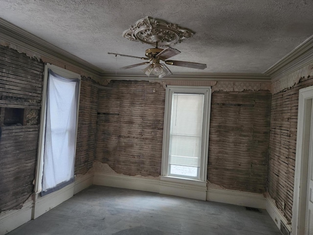 unfurnished room with ceiling fan, crown molding, and a textured ceiling