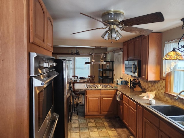 kitchen featuring kitchen peninsula, tasteful backsplash, stainless steel appliances, ceiling fan, and sink